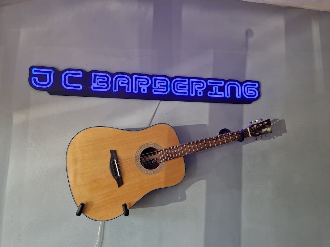 The neon JC Barbering sign and a guitar on the wall inside the shop on Frogmore Lane