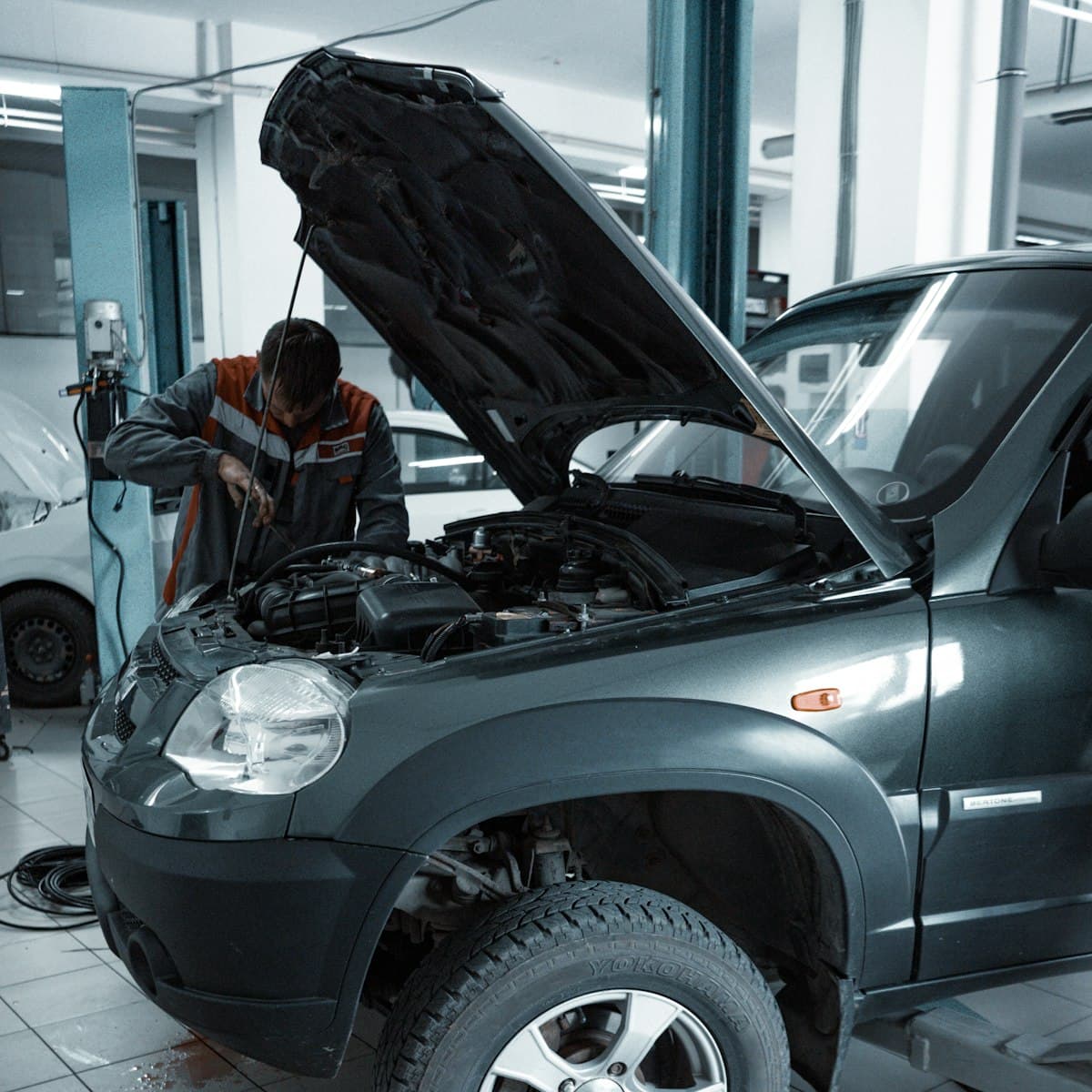 A mechanic working under a car bonnet (representative image)